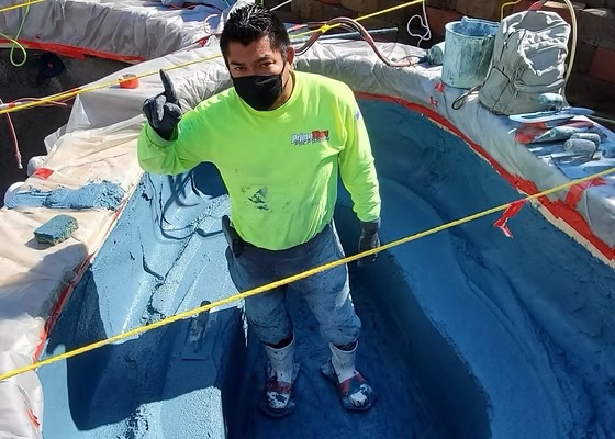 Prime Time crew member standing in a pool freshly troweled with blue plaster